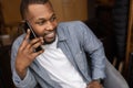 Close-up portrait of happy African American young man having fun talking on cell phone in office, looking to the side Royalty Free Stock Photo