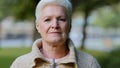 Close up portrait of happy aged beautiful female looking at camera relaxing posing outdoors in cool weather, smiling Royalty Free Stock Photo