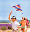 Happy boy flying rainbow kite with his friends Royalty Free Stock Photo