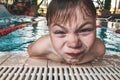 Close-up portrait of happy boy in the swimming pool at aquapark. Cute child having fun enjoyable time on vacation. Looking at cam