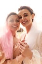 Close up portrait of happy charming bride in a white dress with a white veil and a bridesmaid in a beige dress with pink Royalty Free Stock Photo