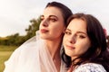 Close up portrait of happy charming bride in a white dress with white veil and a bridesmaid with pink veil hugging each Royalty Free Stock Photo