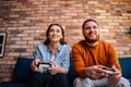 Close-up portrait of happy cheerful young couple holding controllers and playing video games on console sitting together Royalty Free Stock Photo