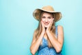 Close up portrait of a happy excited young woman in beach hat with mouth open looking at camera over blue background Royalty Free Stock Photo