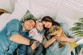 The close-up portrait of the happy family lying with the kid and rabbit on the bed. Above view. Royalty Free Stock Photo