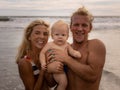 Close up portrait of happy family spending time on the beach. Father and mother holding infant baby boy. Smiling parents. Positive Royalty Free Stock Photo