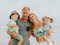 Close up portrait of happy family spending time on the beach. Father and mother holding sons. Cute baby boys. Smiling parents. Royalty Free Stock Photo