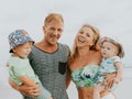 Close up portrait of happy family spending time on the beach. Father and mother holding sons. Cute baby boys. Smiling parents. Royalty Free Stock Photo