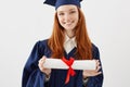 Close up portrait of happy foxy girl graduate in cap smiling holding diploma. Young redhead woman student future lawyer Royalty Free Stock Photo