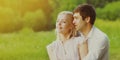 Close up portrait of happy lovely young couple sitting on the grass together looking away over green summer background Royalty Free Stock Photo