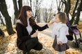 Close up portrait of happy mom and child baby girl, having fun in beautiful autumn park at sunny day, playing, smiling