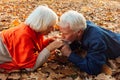 Close up portrait of a happy old man kissing his wife`s hands. In the park in autumn foliage a happy couple is resting