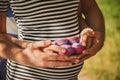 Close up portrait of happy pregnant woman together with husband holding small baby shoes, hugging in summer park Royalty Free Stock Photo