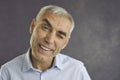 Close up portrait of happy senior man winking happily at camera giving sign that has good offer.