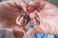 Close up portrait happy sincere middle aged elderly retired family couple making heart gesture with fingers, showing love or Royalty Free Stock Photo