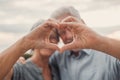 Close up portrait happy sincere middle aged elderly retired family couple making heart gesture with fingers, showing love or Royalty Free Stock Photo