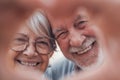 Close up portrait happy sincere middle aged elderly retired family couple making heart gesture with fingers, showing love or Royalty Free Stock Photo