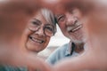 Close up portrait happy sincere middle aged elderly retired family couple making heart gesture with fingers, showing love or Royalty Free Stock Photo