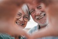 Close up portrait happy sincere middle aged elderly retired family couple making heart gesture with fingers, showing love or Royalty Free Stock Photo