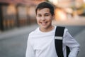 Close up portrait of happy smiled teenage boy in white sweatshirt with backpack outside Royalty Free Stock Photo