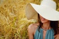 Close-up portrait of a happy smiling woman with long hair and a hat standing in a wheat field. Space for the text Royalty Free Stock Photo