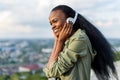 Close-up portrait of happy smiling young black african american woman listening to music. Blurred cityscape on Royalty Free Stock Photo
