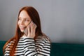 Close-up portrait of happy smiling young woman talking on smartphone at home. Cheerful redhead female making answering Royalty Free Stock Photo