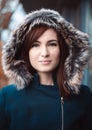 Close up portrait of happy and smilling woman brunette in coat with hood on her hair in winter. Fashion portrait of young model Royalty Free Stock Photo