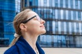 Close-up portrait happy woman in glasses looking away with pensive look in blue Royalty Free Stock Photo
