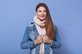 Close up portrait of happy woman wearing denim jacket and scarf, posing isoalted over blue background, lady with positive facial