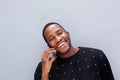 Close up happy young african man against wall talking on cell phone Royalty Free Stock Photo
