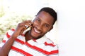 Happy young man leaning to wall and talking on cell phone Royalty Free Stock Photo