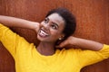 Close up happy young black woman smiling with hands behind head against brown background Royalty Free Stock Photo