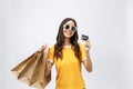 Close-up portrait of happy young brunette woman in sunglasses holding credit card and colorful shopping bags, looking at Royalty Free Stock Photo