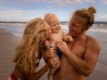 Close up portrait of happy young Caucasian family. Father holding baby boy. Mother kissing their son. Family time on the beach. Royalty Free Stock Photo