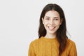 Close-up portrait of happy young european woman smiling broadly wearing yellow sweater and standing over gray background Royalty Free Stock Photo