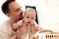 Close-up portrait of happy young father hugging and kissing his sweet adorable newborn child. Indoors shot, concept Royalty Free Stock Photo
