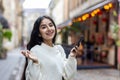 Close-up portrait of a happy young Indian woman standing on a city street, holding a phone in her hands, happy with the Royalty Free Stock Photo