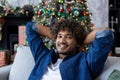 Close-up portrait of a happy young male student sitting on the couch with his hands behind his head. Looking forward Royalty Free Stock Photo