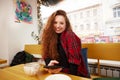 Close-up portrait of happy young woman making selfie on mobile phone sitting at table with laptop by window in cafe Royalty Free Stock Photo