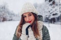 Close up portrait of happy young woman in snowy winter park wearing warm knitted clothes and red festive lipstick. Royalty Free Stock Photo