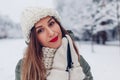 Close up portrait of happy young woman in snowy winter park wearing warm knitted clothes and red festive lipstick. Royalty Free Stock Photo