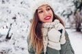 Close up portrait of happy young woman in snowy winter park wearing warm knitted hat scarf and red festive lipstick. Royalty Free Stock Photo