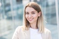 Close-up portrait of a happy young woman standing outdoors and smiling on blurred urban background looking at camera. Female Royalty Free Stock Photo