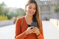 Close up portrait of a happy young woman walking in the city sending text message on cellphone