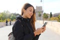 Close up portrait of a happy young woman walking in the city sending text message on phone in autumn or winter