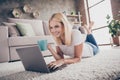 Close-up portrait of her she nice attractive charming cheerful focused mature lady lying on carpet drinking tea using Royalty Free Stock Photo