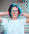 Close-up portrait of a hipster girl wearing glasses with blue hair. Atypical beauty. Street fashion