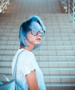 Close-up portrait of a hipster girl wearing glasses with blue hair. Atypical beauty. Street fashion.