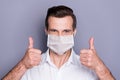 Close-up portrait of his he attractive healthy content guy wearing safety cotton mask showing two double thumbup stop